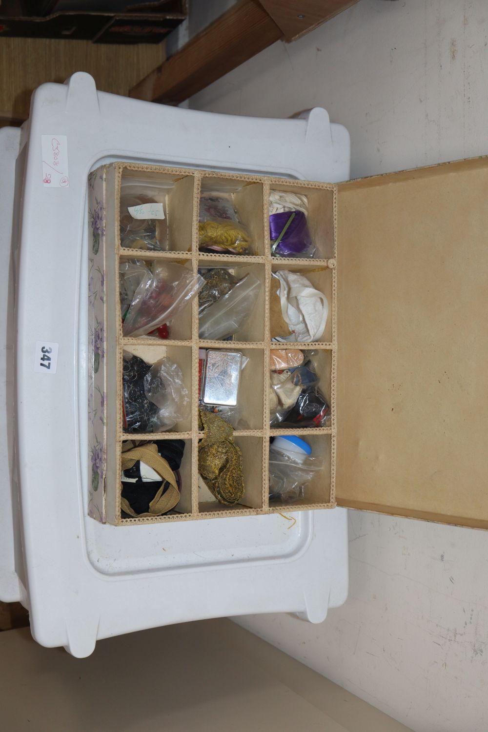 A three drawer trolley containing various dolls wigs, lengths of ribboning, braiding etc